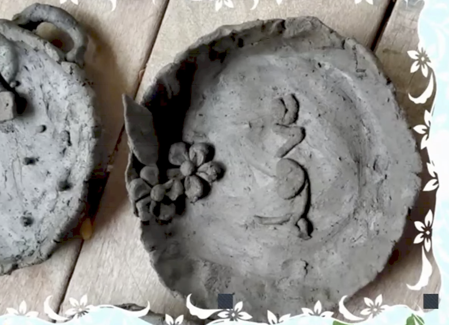 Two clay vessels decorated with flowers and patterns added by others